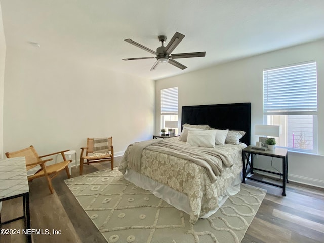 bedroom with multiple windows, wood-type flooring, and ceiling fan