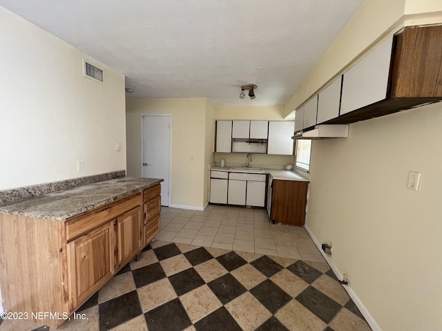 kitchen featuring sink, light tile patterned floors, and a textured ceiling