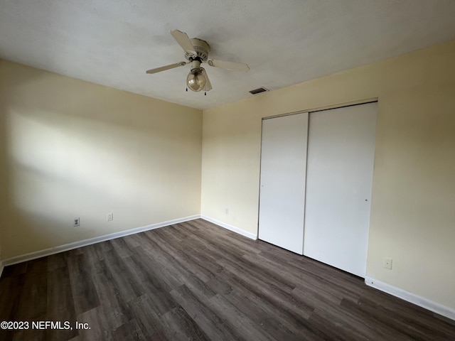 unfurnished bedroom featuring dark hardwood / wood-style flooring, a closet, and ceiling fan