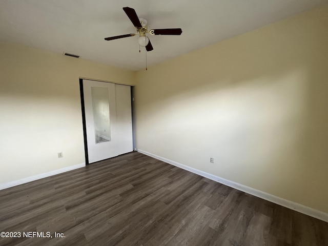 unfurnished bedroom featuring a closet, dark wood-type flooring, and ceiling fan