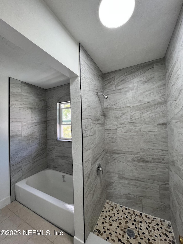 bathroom with tile patterned floors, a tile shower, and a textured ceiling