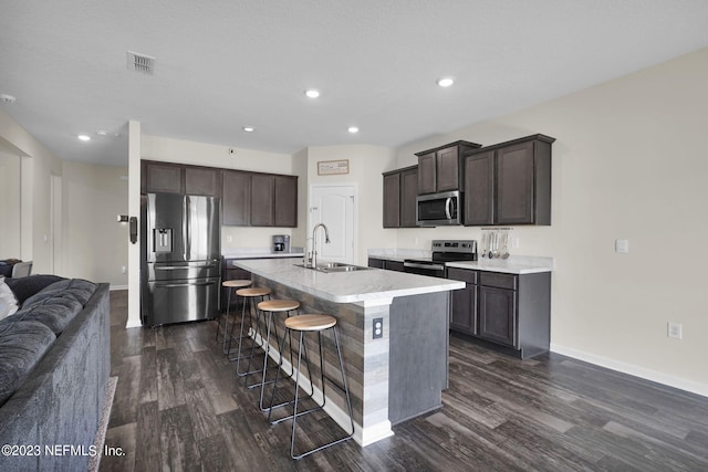 kitchen featuring dark brown cabinets, stainless steel appliances, sink, and a center island with sink