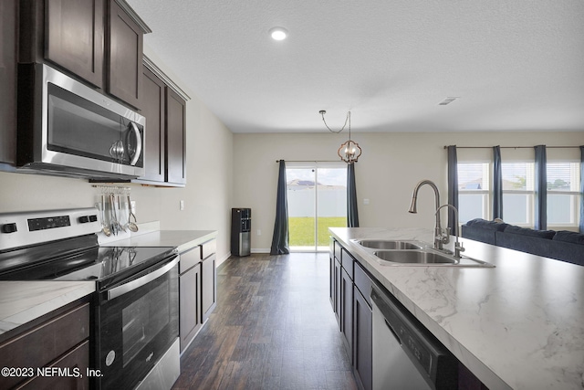 kitchen with appliances with stainless steel finishes, dark hardwood / wood-style floors, sink, hanging light fixtures, and dark brown cabinetry