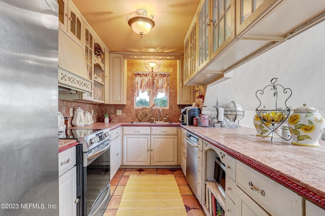 kitchen featuring light tile patterned floors, sink, appliances with stainless steel finishes, tile counters, and decorative backsplash