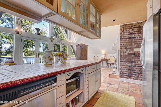 kitchen with appliances with stainless steel finishes, tile counters, and french doors