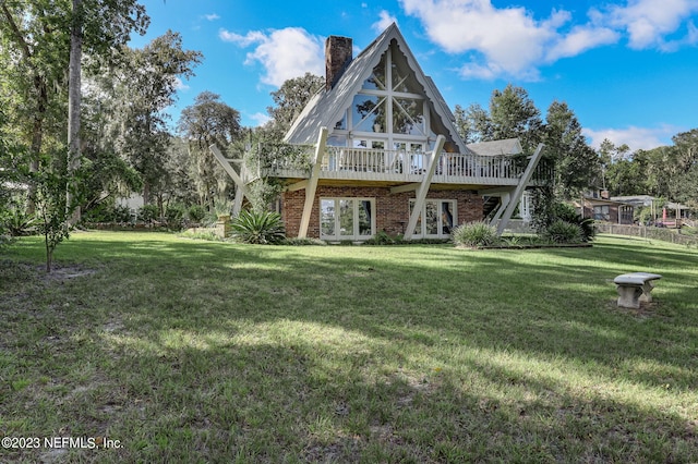 back of property featuring a deck and a lawn