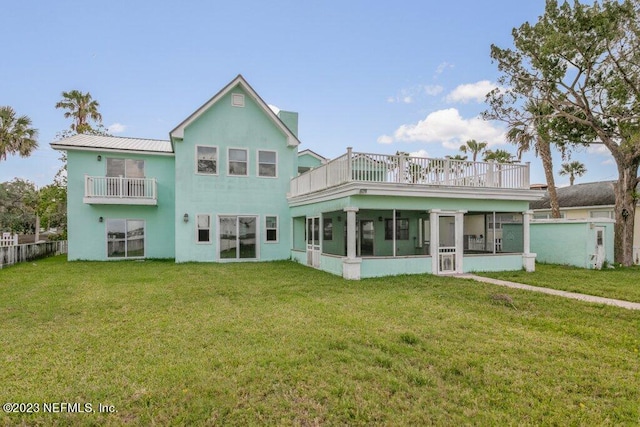 rear view of house featuring a balcony, a sunroom, and a lawn