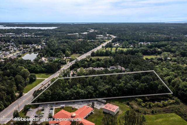 birds eye view of property featuring a water view and a wooded view