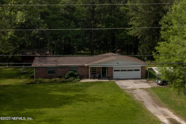 single story home with a garage, brick siding, driveway, a forest view, and a front lawn