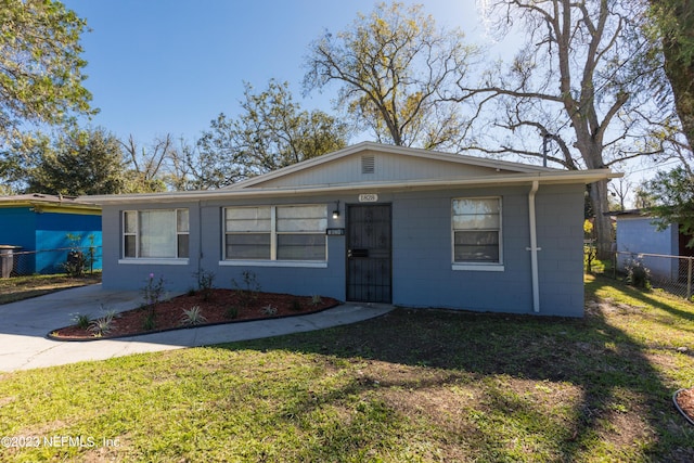 view of front of home with fence, concrete block siding, a front lawn, and concrete driveway