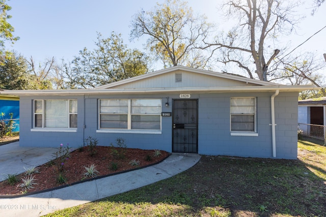 view of front of home featuring concrete block siding and fence