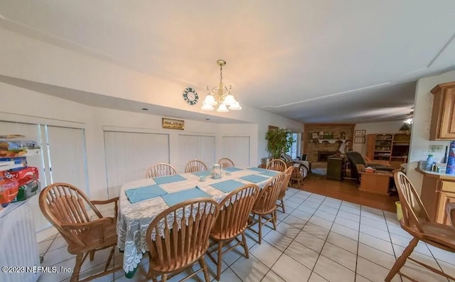 dining space featuring a notable chandelier, a fireplace, and light tile patterned floors