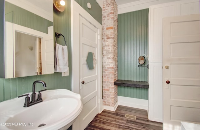 bathroom with ornamental molding, sink, and wood-type flooring