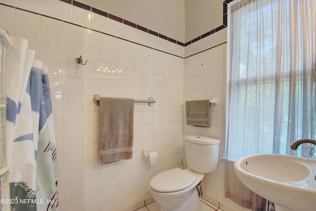 bathroom featuring sink, tile walls, and toilet