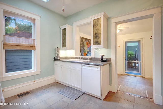 kitchen with white cabinetry, sink, light tile patterned floors, and white dishwasher