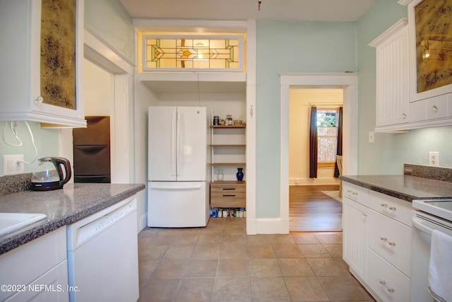 kitchen with white cabinets, dark stone countertops, white appliances, and light tile patterned floors