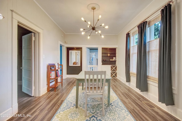 dining space with hardwood / wood-style floors, crown molding, and a notable chandelier