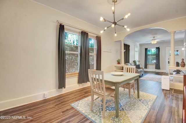 dining space with hardwood / wood-style floors, crown molding, and decorative columns