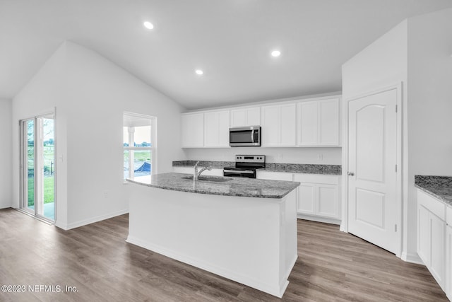 kitchen with stainless steel appliances, light stone countertops, vaulted ceiling, a sink, and wood finished floors