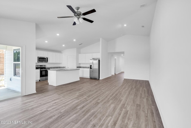 kitchen with light wood finished floors, a center island with sink, appliances with stainless steel finishes, and open floor plan