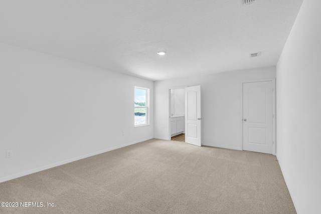 unfurnished bedroom featuring light colored carpet, visible vents, baseboards, and a textured ceiling