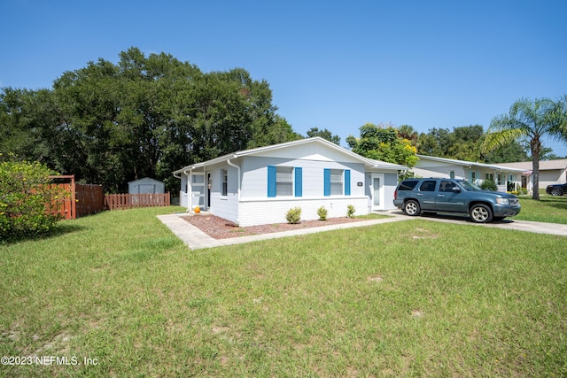 ranch-style home featuring brick siding, driveway, a front yard, and fence