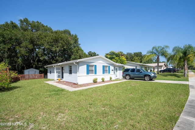 ranch-style home featuring a front yard, concrete driveway, brick siding, and fence