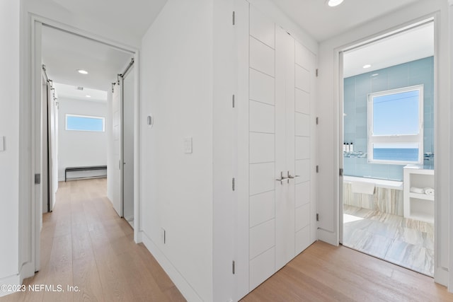 hallway featuring a barn door, a baseboard radiator, and light hardwood / wood-style flooring