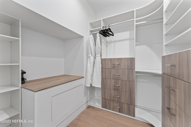 walk in closet with light hardwood / wood-style floors