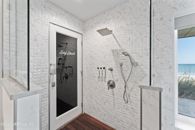 bathroom featuring hardwood / wood-style flooring, a healthy amount of sunlight, a water view, and a tile shower