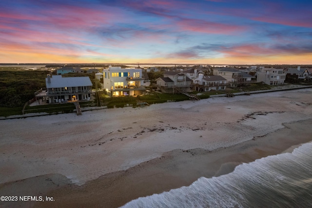 aerial view at dusk with a view of the beach and a water view