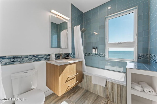 full bathroom featuring hardwood / wood-style flooring, shower / tub combo with curtain, vanity, and toilet