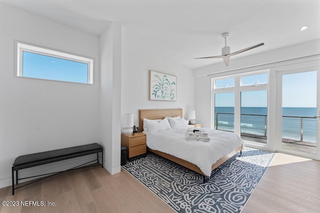 bedroom featuring access to outside, multiple windows, ceiling fan, and a water view