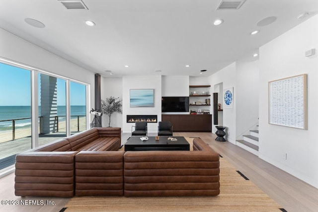 living room with light wood-type flooring and a water view