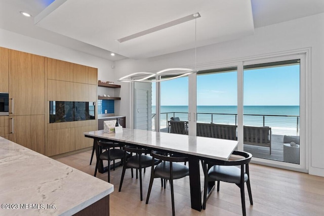 dining room with light hardwood / wood-style flooring and a water view