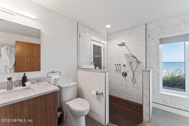 bathroom with a tile shower, vanity, and toilet