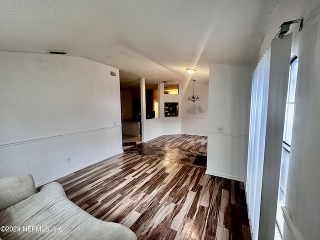 unfurnished living room featuring hardwood / wood-style floors, vaulted ceiling, and a textured ceiling