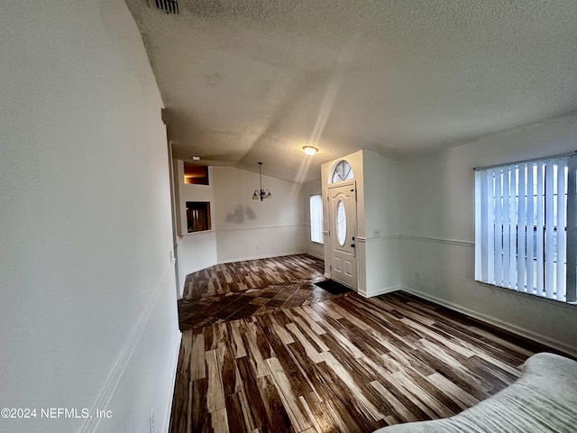 foyer entrance featuring lofted ceiling, dark hardwood / wood-style floors, and a textured ceiling