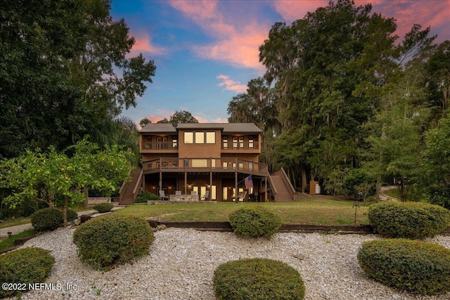 back house at dusk featuring a deck and a yard