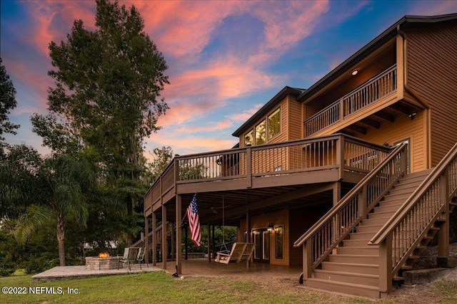 back house at dusk featuring a patio, a yard, and a wooden deck