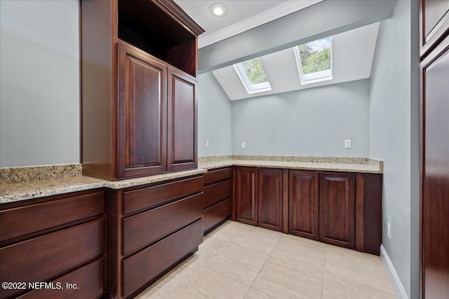 interior space with crown molding, lofted ceiling with skylight, and tile patterned flooring