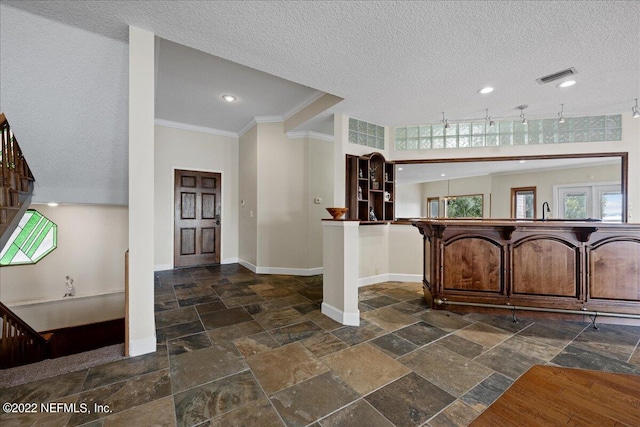 foyer entrance featuring a textured ceiling, crown molding, and sink