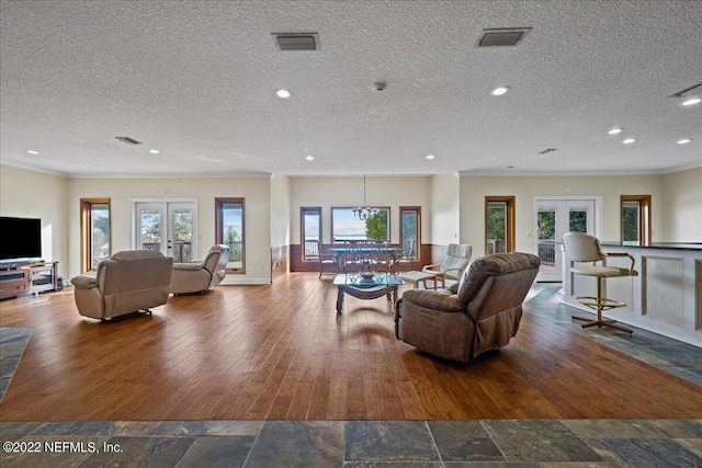 living room featuring a healthy amount of sunlight, a textured ceiling, hardwood / wood-style flooring, and french doors