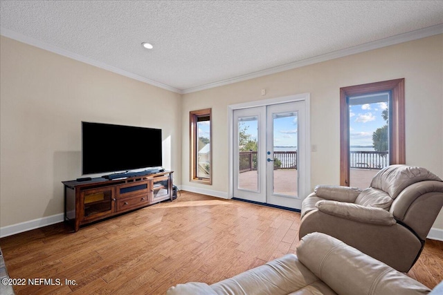 living room featuring french doors, a textured ceiling, light hardwood / wood-style flooring, and ornamental molding