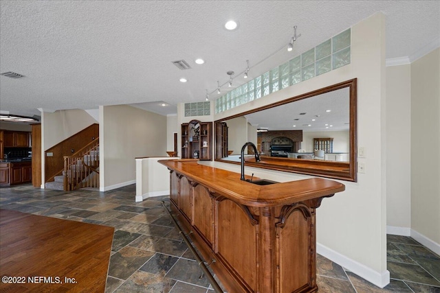 kitchen featuring ornamental molding, a textured ceiling, a center island, and sink