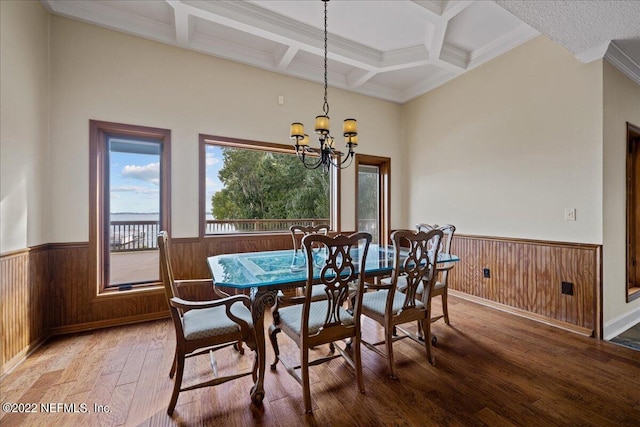 dining space with a notable chandelier, wood walls, coffered ceiling, and hardwood / wood-style flooring