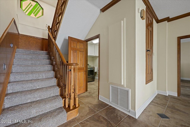 stairway with a textured ceiling, crown molding, and tile patterned floors