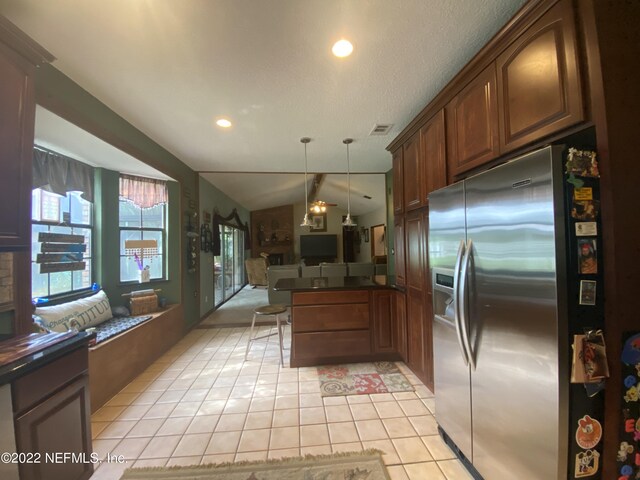 kitchen with decorative light fixtures, lofted ceiling, kitchen peninsula, light tile patterned flooring, and stainless steel refrigerator with ice dispenser