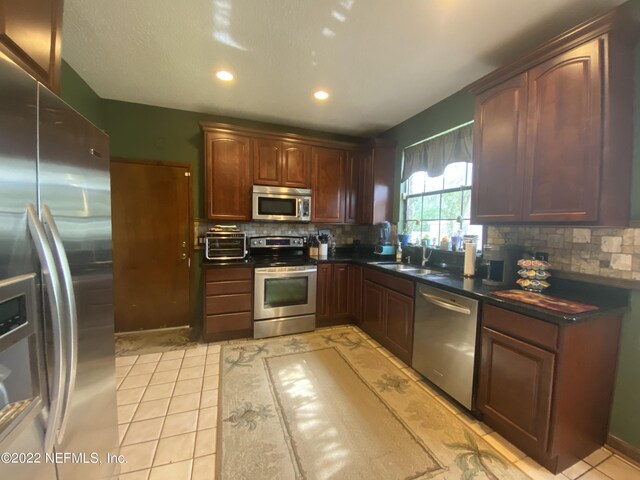 kitchen with stainless steel appliances, sink, backsplash, and light tile patterned flooring