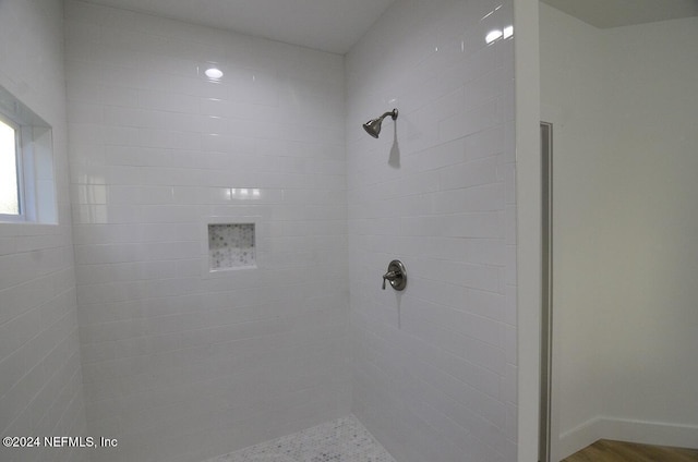 bathroom with a tile shower and hardwood / wood-style flooring